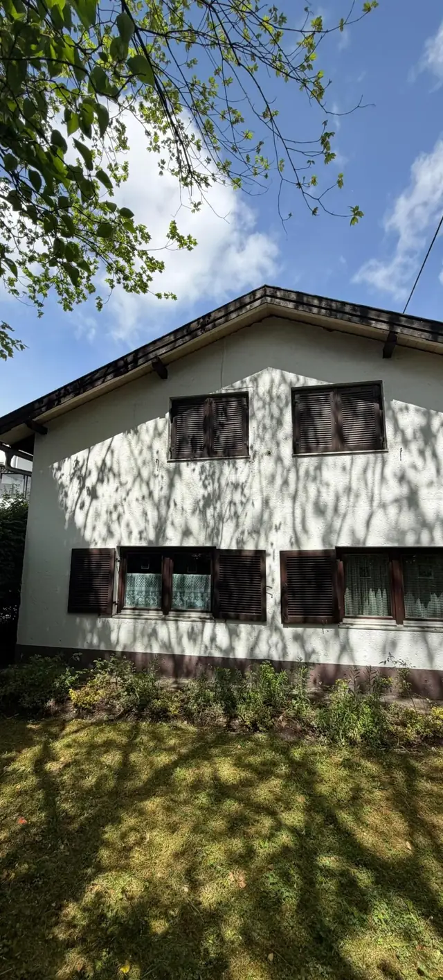 Hausfassade mit Holzdachrand und Fensterläden